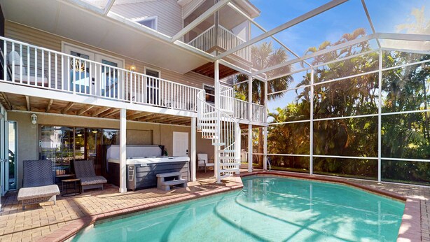 Área da piscina com deck coberto, área de estar externa e vista para as árvores ao redor.