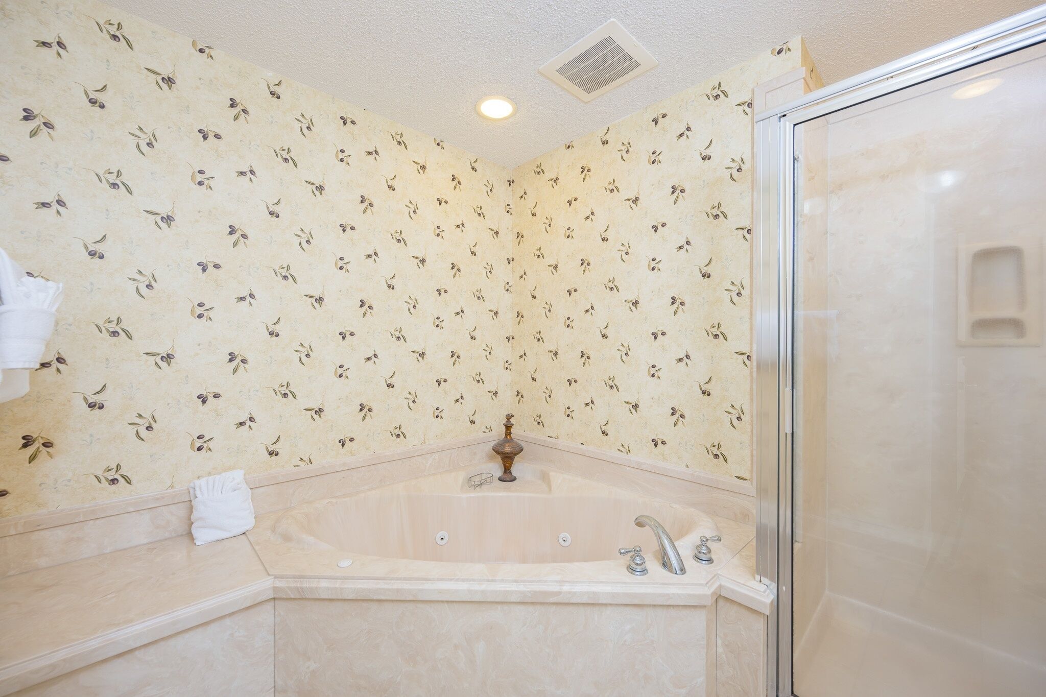 A bathroom with a bathtub, a shower, and a patterned wall.