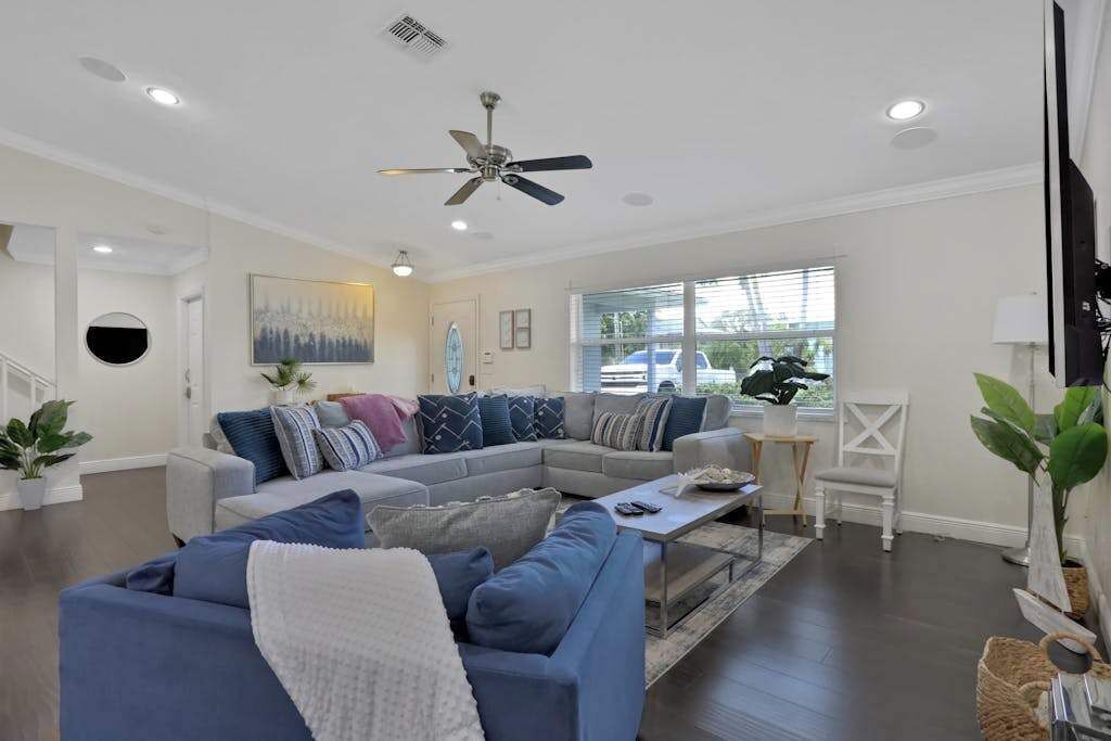 A modern living room with a sectional sofa, a coffee table, and a ceiling fan.