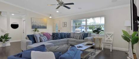 A modern living room with a sectional sofa, a coffee table, and a ceiling fan.