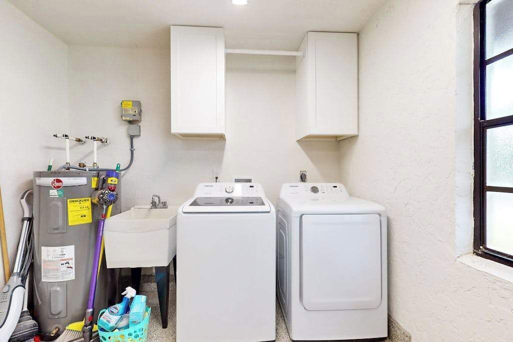 Een wasserette met twee wasmachines, een gootsteen en een gas- en watermeter.