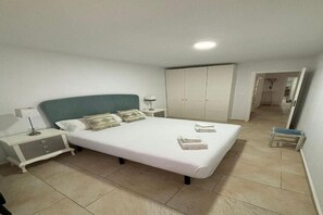 A bedroom with a bed, nightstands, a wardrobe, and a small stool. - Wonderful apartment in Triana, Purity (Sevilla)