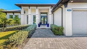 Ein modernes, zweistöckiges Haus mit Auffahrt zu einer blauen Tür, einer Garage und einem gepflegten Garten.