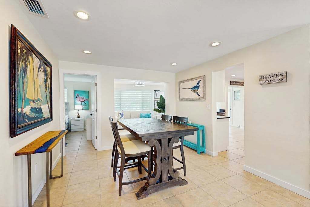 A dining area with a wooden table and chairs, a bench, and a painting on the wall.