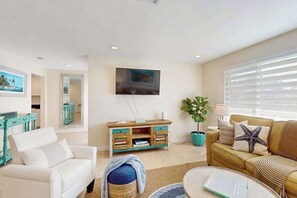 A living room with a sofa, a coffee table, a TV, and a wooden cabinet. - Charming home near the ocean with gas grill, AC & Wifi (Bokeelia)