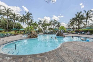 A swimming pool with palm trees, lounge chairs, and a clear sky. - Spacious 2nd-floor condo with lake/golf view - walk to restaurant, tennis & pool (Naples)