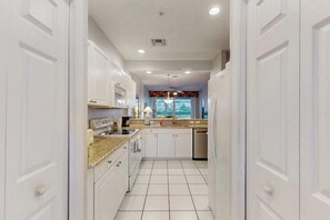 A kitchen with white cabinets, a granite countertop, and a tiled floor. - Spacious 2nd-floor condo with lake/golf view - walk to restaurant, tennis & pool (Naples)