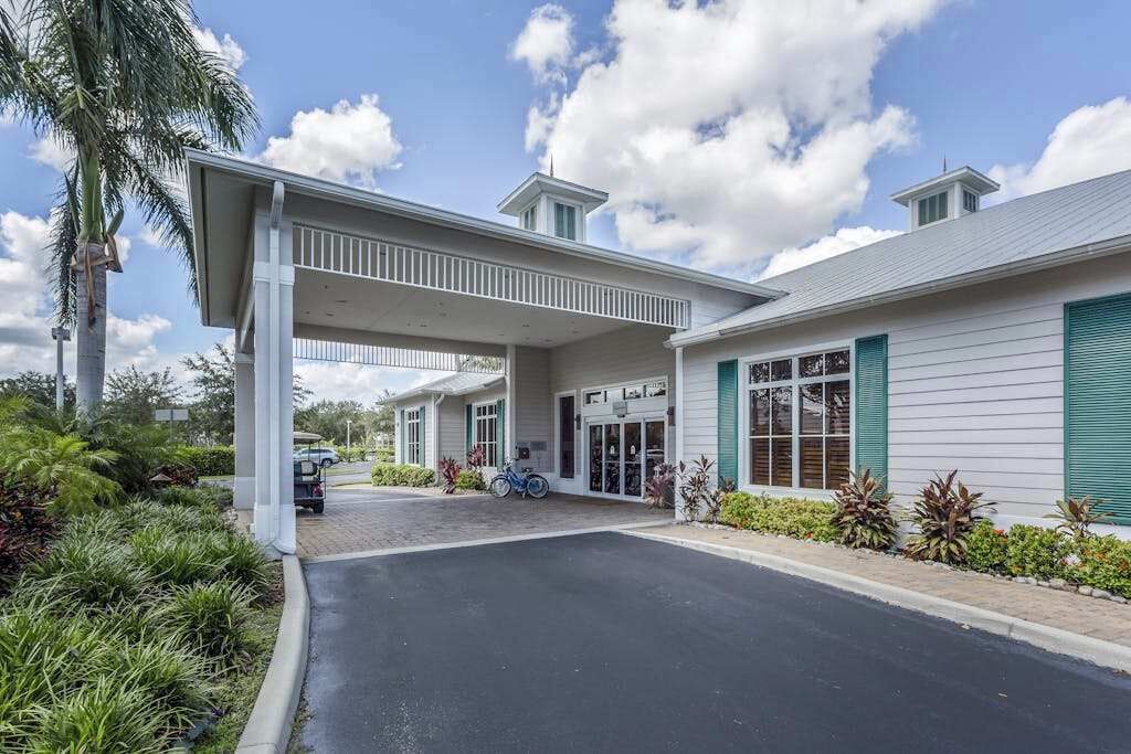 A hotel with a covered entrance, a parking area, and a well-maintained garden.