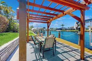 Eine Holzterrasse mit Gartenmöbeln, einem Pool und Blick auf das Wasser.