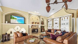 Ein Wohnzimmer mit Ledersofas, einem Kamin, einem Fernseher und dekorativen Regalen.