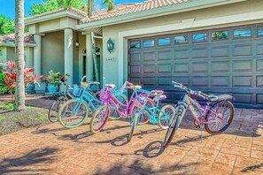 A residential garage with a number plate, a driveway, and a row of bicycles. - Custom waterfront home w/ dock, heated pool, AC & amazing indoor/outdoor spaces (Cape Coral)