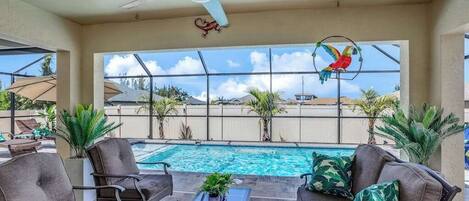 Zona junto a la piscina con sillones de descanso, ventilador de techo y vistas a la piscina.
