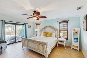 A bedroom with a bed, a ceiling fan, a nightstand, a chair, and a window with blinds. - Canalfront Home with WiFi, Private Pool, & Dock w/ Gulf + River Access - Dogs OK (Cape Coral)