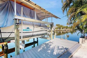 A boat named 'Rebates' docked at a pier with a covered area and a wooden deck. - Canalfront Home with WiFi, Private Pool, & Dock w/ Gulf + River Access - Dogs OK (Cape Coral)