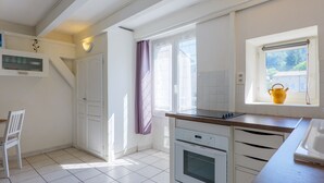 A kitchen with a stove, oven, and a window with a curtain. - Charming One-Bedroom Apartment in the Heart of Vals-les-Bains (Vals-les-Bains)