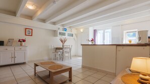 A spacious living area with a wooden table, a dining table, and a kitchen area with a window. - Charming One-Bedroom Apartment in the Heart of Vals-les-Bains (Vals-les-Bains)
