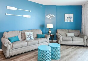 A living room with two sofas, a lamp, and decorative wall art. - 2BR~ Lagoon Pool~ Palms of Destin 21211 (Destin)