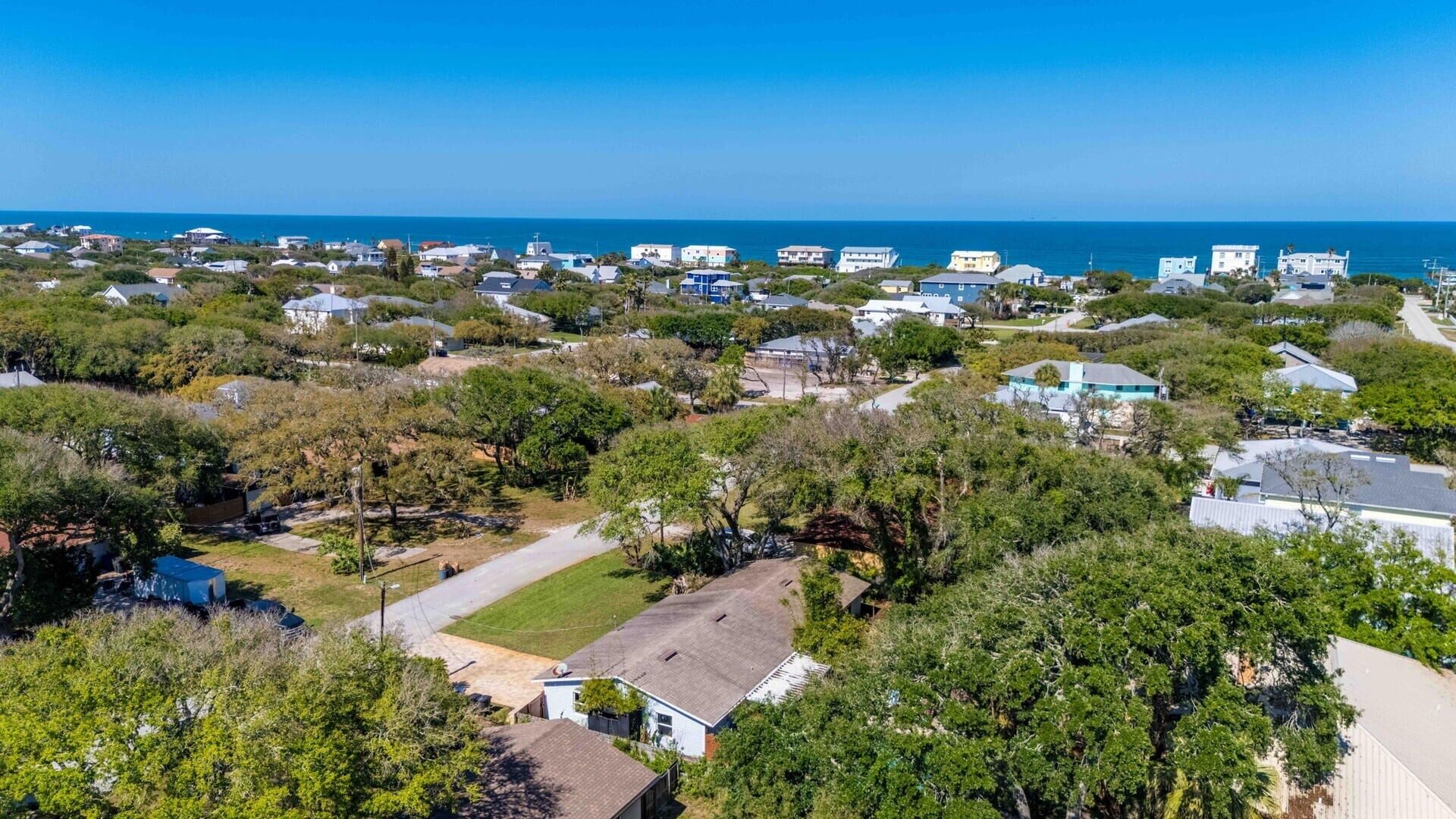 A residential area with houses, trees, and a clear view of the ocean.