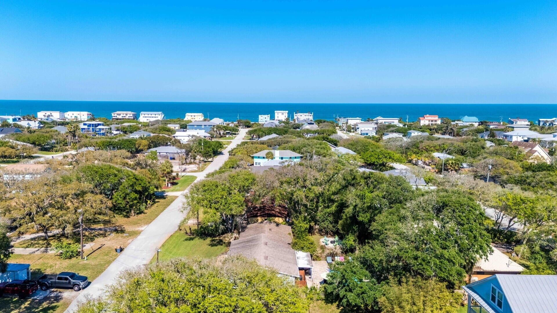 Luftaufnahme einer Küstenwohngegend mit Häusern, blauem Himmel und dem Meer im Hintergrund.