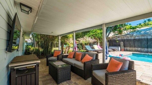 A covered patio with wicker furniture, a pool, and a view of the backyard. - Vilano Beach I Ocean - Private Pool - Fire Pit 3 Bedroom Home (St. Augustine)