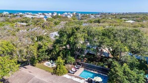 A residential area with a swimming pool surrounded by trees and a view of the ocean. - Vilano Beach I Ocean - Private Pool - Fire Pit 3 Bedroom Home (St. Augustine)