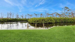 A serene lakeside view with a grassy area, trees, and a clear sky. - Waterfront & ground-floor home with free WiFi, dock, pool, & central AC (Englewood)