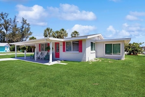 A single-story house with a covered patio, a red door, and a number '1255' on the wall. - Waterfront home with canal views, patio, sun room, & central AC - near beach (Englewood)