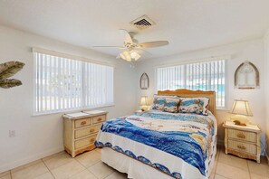 A bedroom with a bed, two bedside tables, a ceiling fan, and large windows. - Waterfront home with canal views, patio, sun room, & central AC - near beach (Englewood)