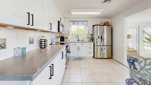 Een moderne keuken met witte kasten, roestvrijstalen apparatuur en een groot raam.