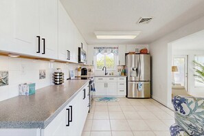 A modern kitchen with white cabinets, stainless steel appliances, and a large window. - Waterfront home with canal views, patio, sun room, & central AC - near beach (Englewood)