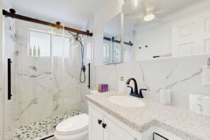 A bathroom with a shower, toilet, sink, and a large mirror. - Waterfront home with canal views, patio, sun room, & central AC - near beach (Englewood)