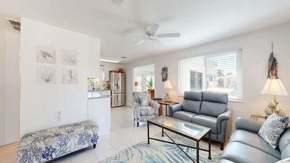 A living room with a sofa, armchair, coffee table, and artwork on the walls. - Waterfront home with canal views, patio, sun room, & central AC - near beach (Englewood)