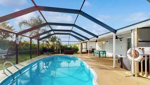 A covered swimming pool with a glass enclosure, outdoor seating, and a lifebuoy. - Centrally located duplex with on-site pool, firepit, patio, & BBQ - dog-friendly (Cape Coral)