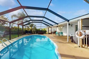 A covered swimming pool with a glass enclosure, outdoor seating, and a lifebuoy. - Centrally located duplex with on-site pool, firepit, patio, & BBQ - dog-friendly (Cape Coral)