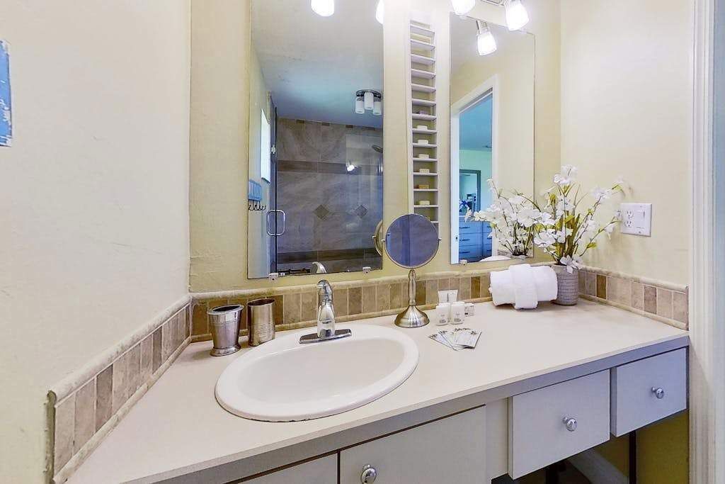 A bathroom with a sink, mirror, and toiletries.