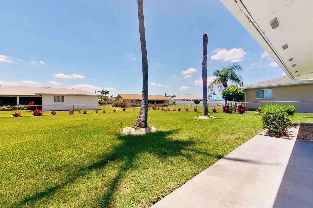 Una zona residencial con casas, césped cuidado y palmeras.