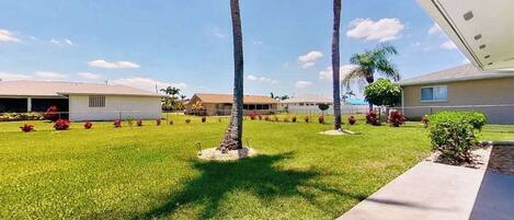 Una zona residencial con casas, césped cuidado y palmeras.