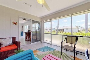 A spacious room with a large sliding glass door leading to a balcony, a ceiling fan, and a dining area visible through the door. - Dog-friendly home with screened lanai, central AC, & washer/dryer (Cape Coral)