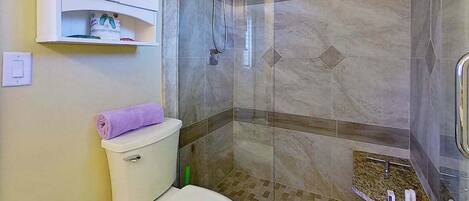 A bathroom with a toilet, a shower, and a sink.