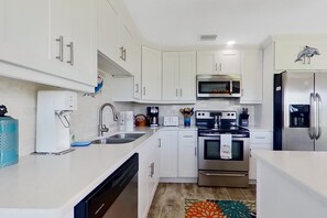 A modern kitchen with white cabinets, stainless steel appliances, and a colorful rug. - Dog-friendly home with screened lanai, central AC, & washer/dryer (Cape Coral)