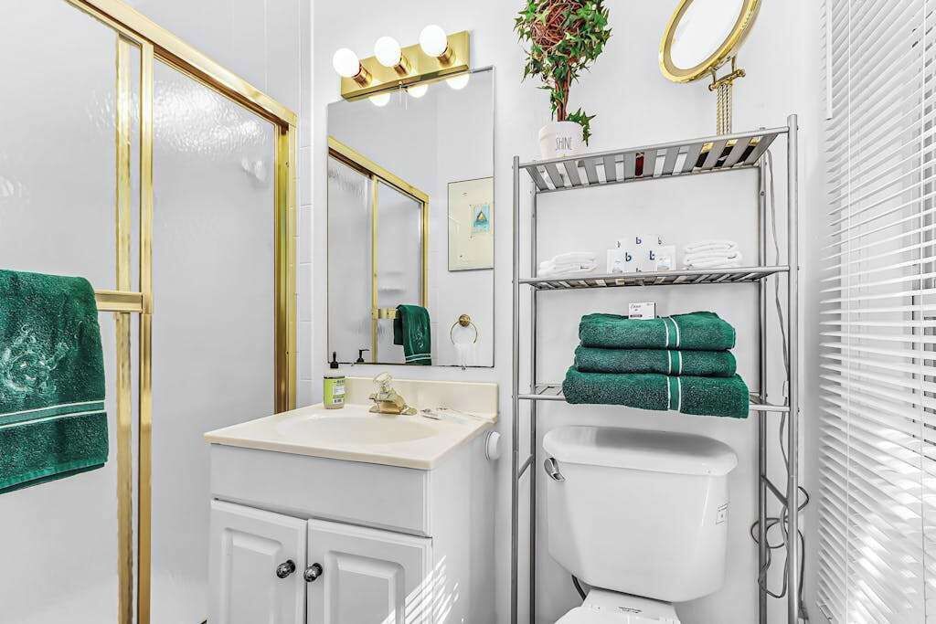 A bathroom with a sink, mirror, vanity, toilet, and towel rack.