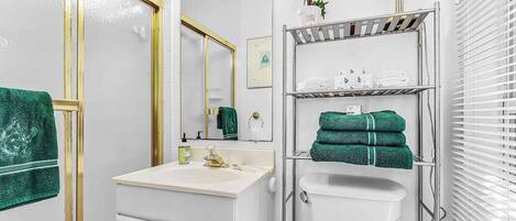 A bathroom with a sink, mirror, vanity, toilet, and towel rack.