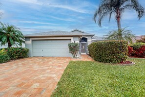 A residential house with a garage, a well-maintained lawn, and a palm tree. - Waterside Home with Private Covered Pool & Patio - Golf Courses Nearby (Fort Myers)