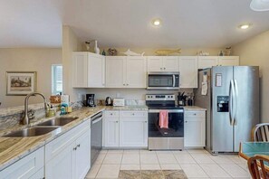 A kitchen with white cabinets, a stainless steel refrigerator, a microwave, an oven, and a sink. - Waterside Home with Private Covered Pool & Patio - Golf Courses Nearby (Fort Myers)
