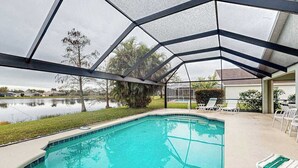 Una piscina con cerramiento de vidrio, rodeada por una zona verde y una extensión de agua.