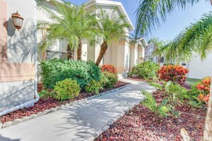 A building with a pathway, palm trees, and various plants. - Spacious home with screened-in pool & lush lakefront views - minutes to beaches (Fort Myers)