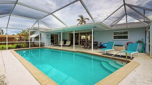 Una piscina con zona techada, sillas de descanso y vistas al exterior.