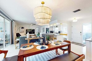 Eine moderne Küche mit einer zentralen Kochinsel, einem Essbereich mit Holztisch und einer großen Chandelier.