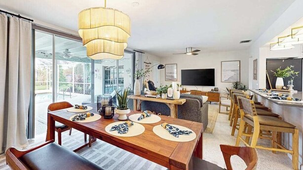 Un comedor moderno con una mesa de madera, sillas e iluminación colgante grande.