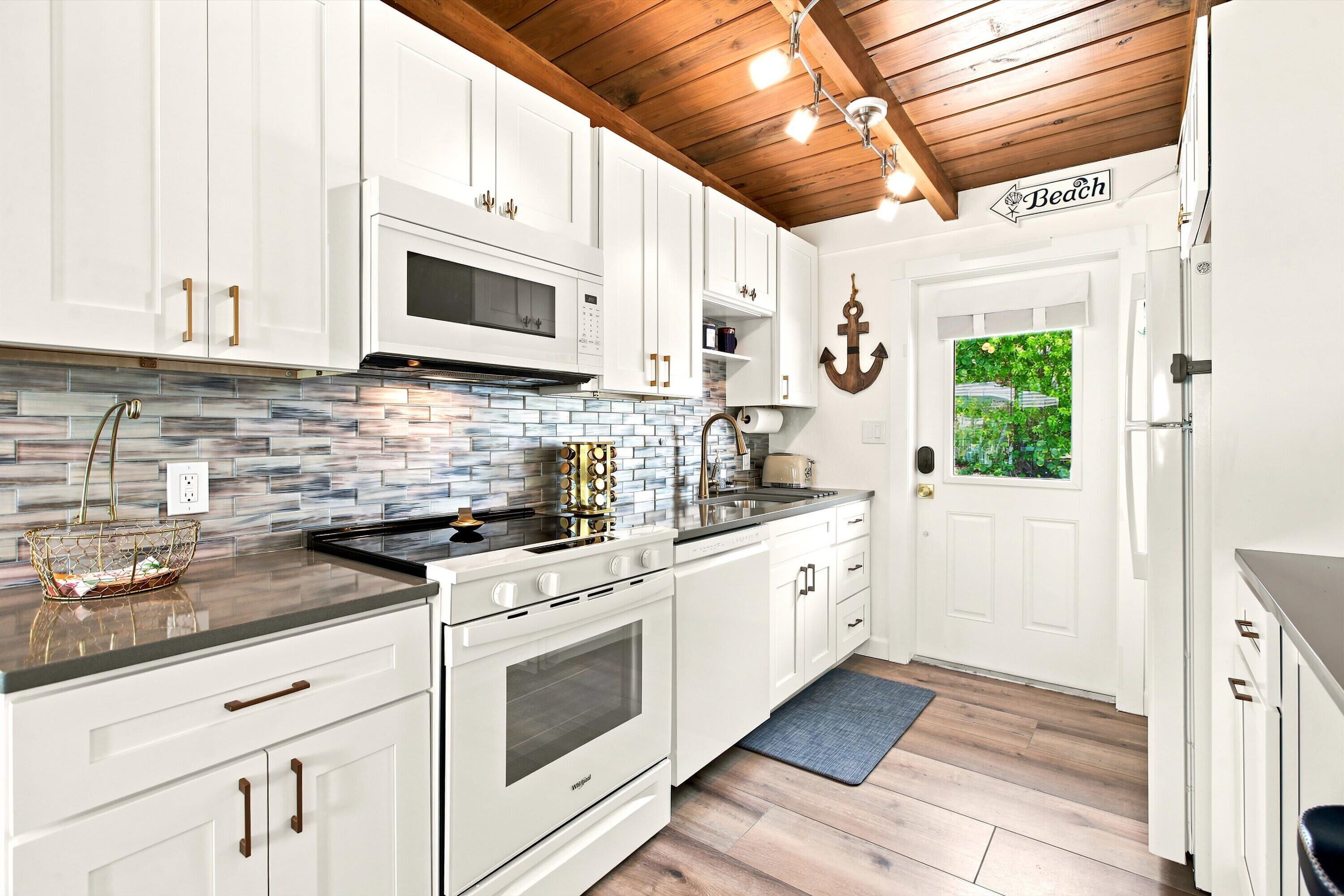 A kitchen with white cabinets, a wooden ceiling, and a sign indicating a beach view.